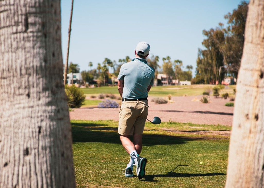 A golfer walking a palm-lined fairway